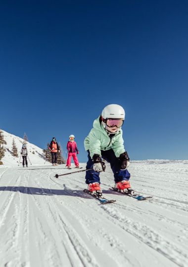 Child skiing happily on a sunny slope in the Ski Juwel