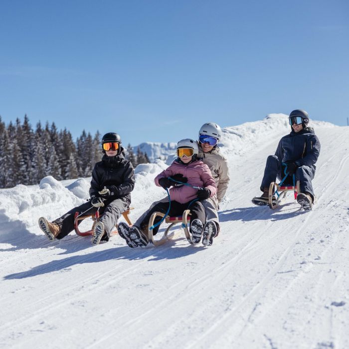 Familie rodelt auf der Naturrodelbahn im Ski Juwel